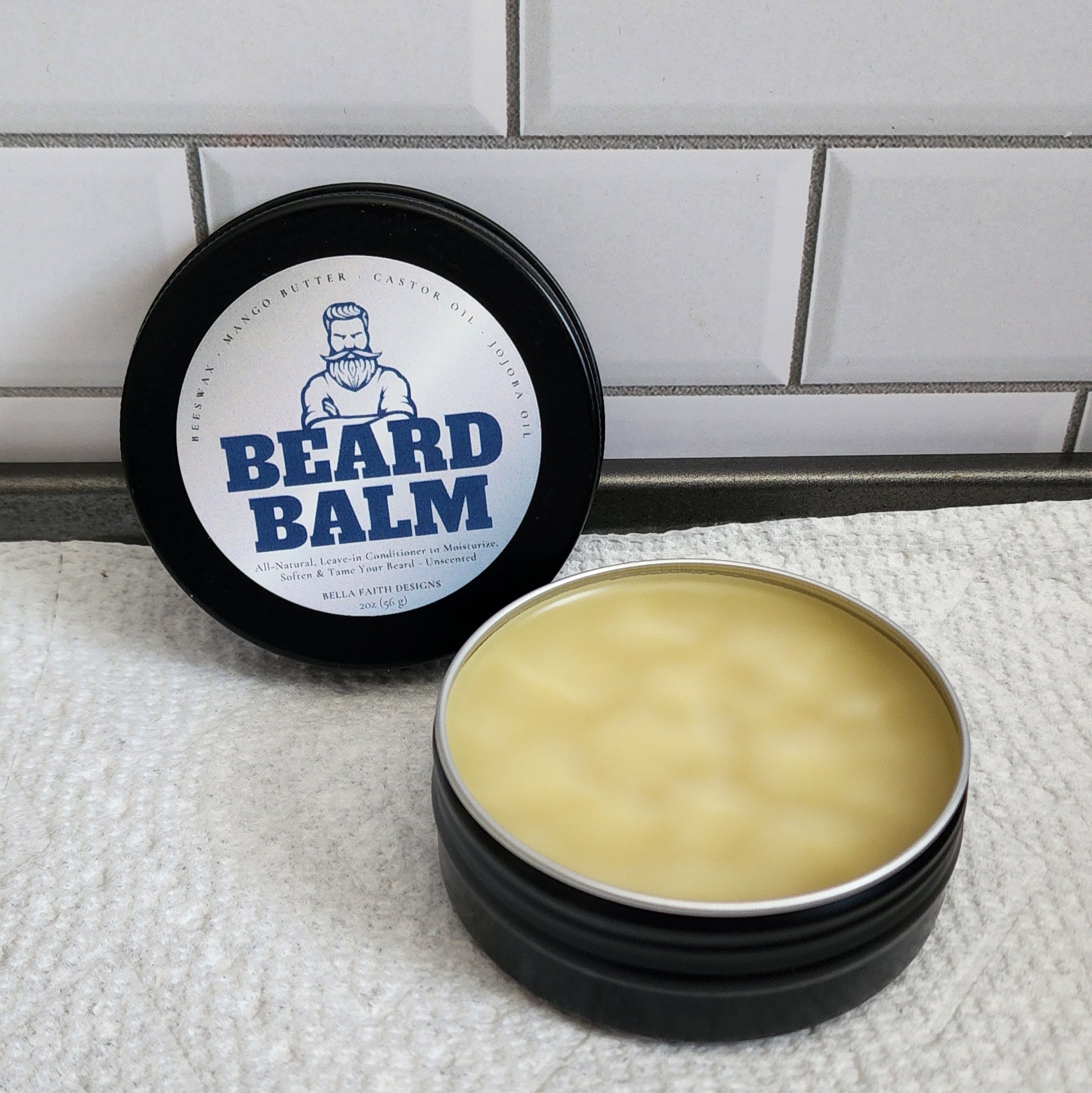 A 2oz black aluminum jar with a screw on lid that shows a label for Beard Balm.